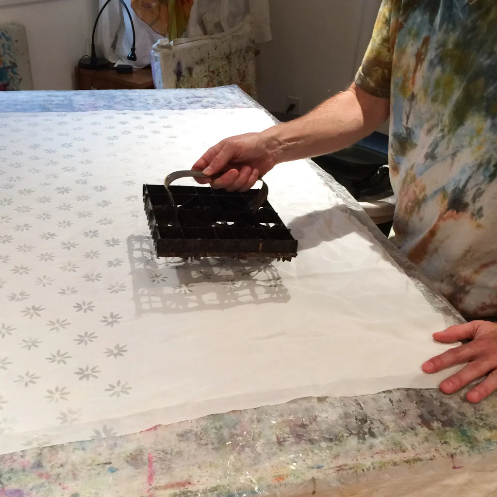 Adding soy wax resist to silk crepe de chine using an Indonesian tjap. The wax will block whatever color I add next. 