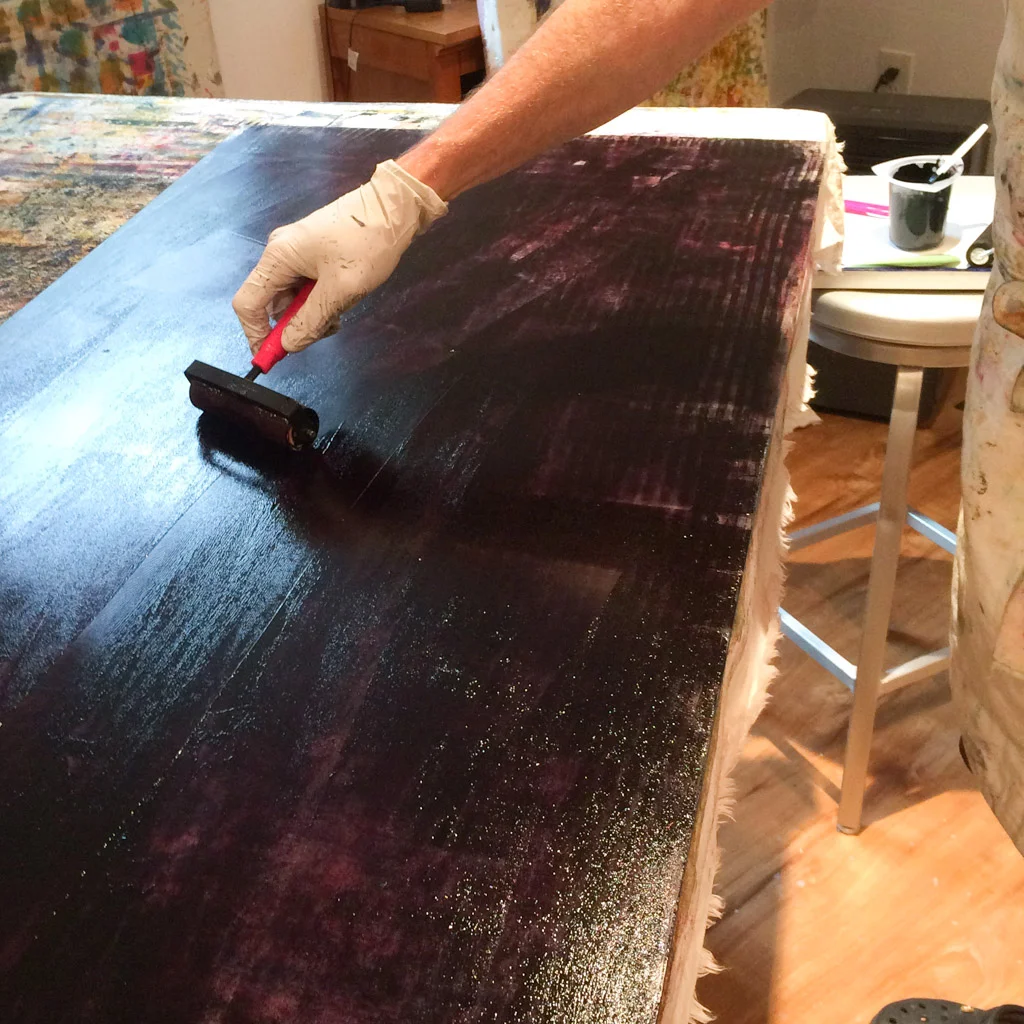 Inking a large sheet of plexiglass with thickened dye for monotype printing.