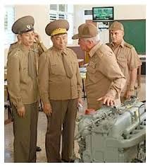 Col. PANG Myong Cha, Deputy Airport Director, left, RI Yongho, Director General Bureau of Surveillance, Chief to General Staff of Korean People's Army DPRK, right, discuss aeroplane maintenance with Russian mechanics.