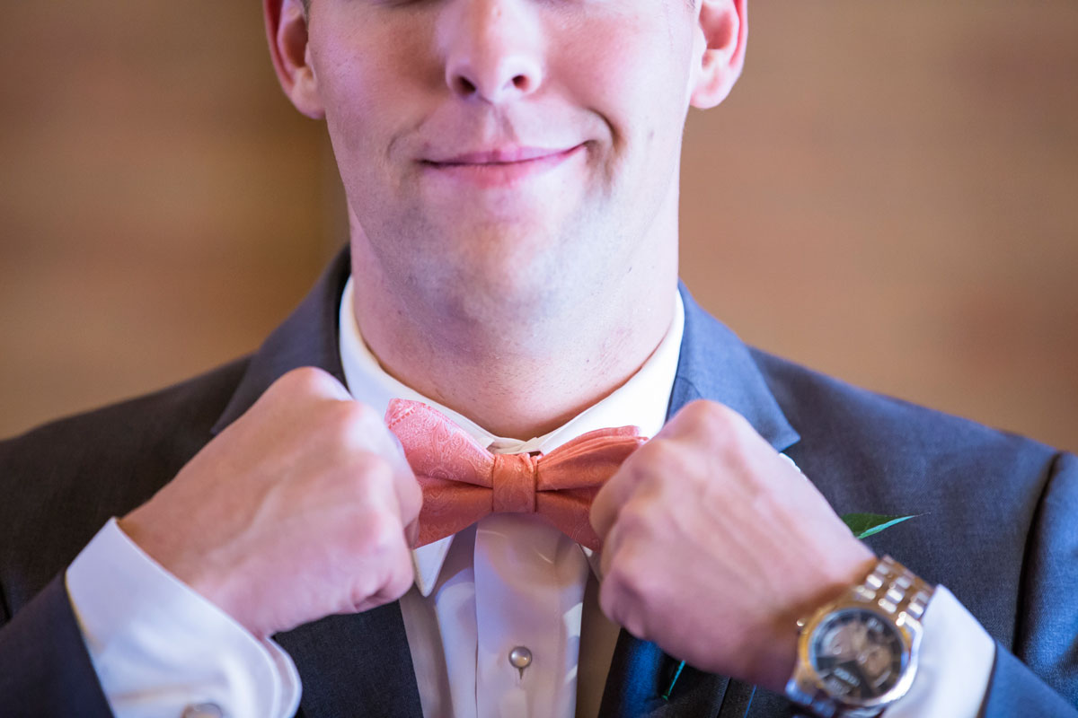 The handsome groom adjusting his bow tie. 