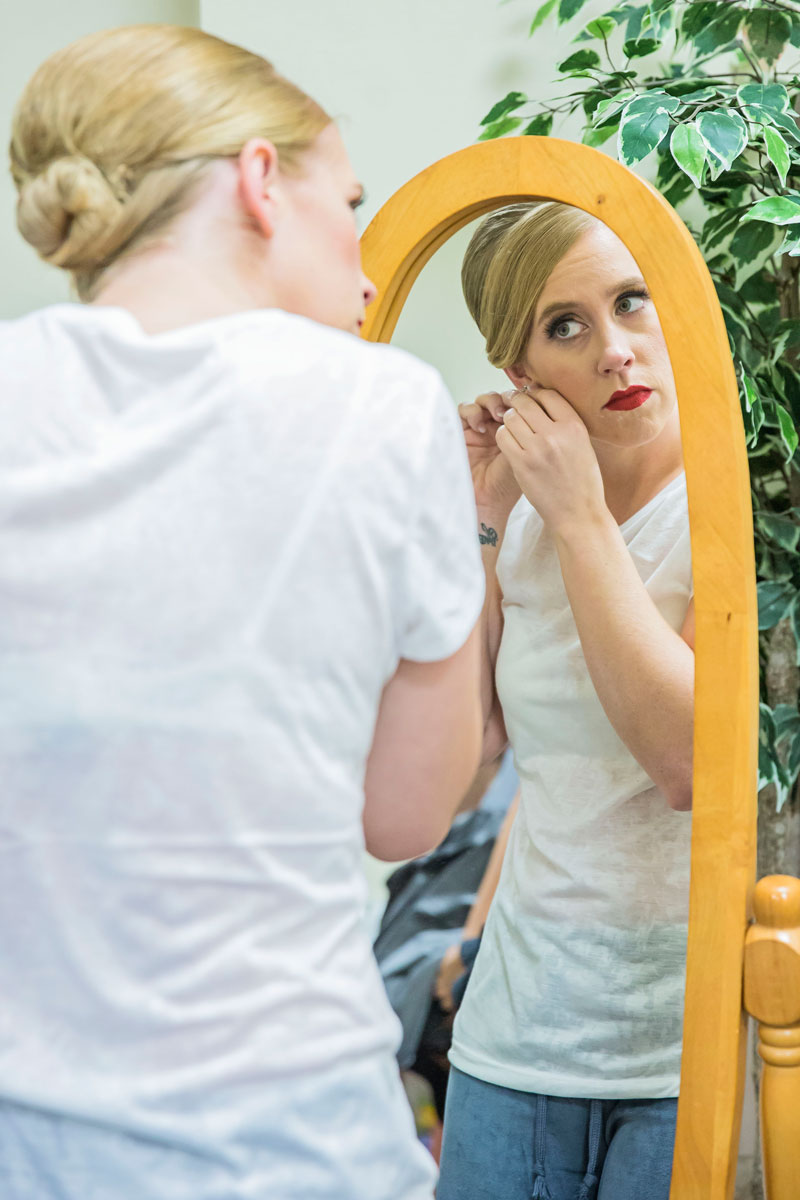 Beautiful bride, putting on the finishing touches before the dress goes on.