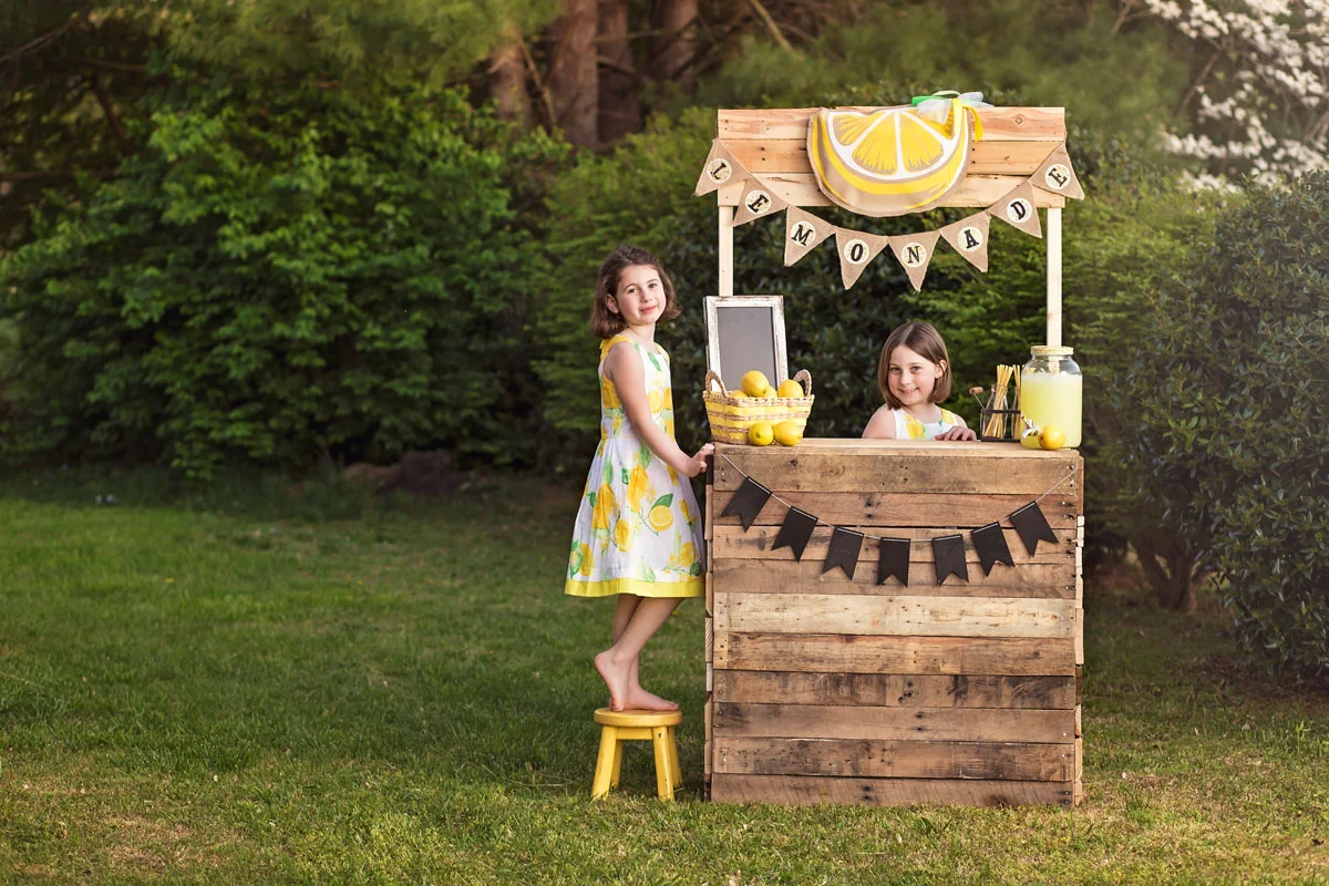 sisters-laughing-together-lemonade-stand-maryville-photographer.jpg