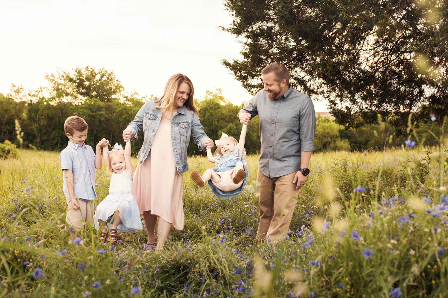 Parents swinging little girls during family pictures. 