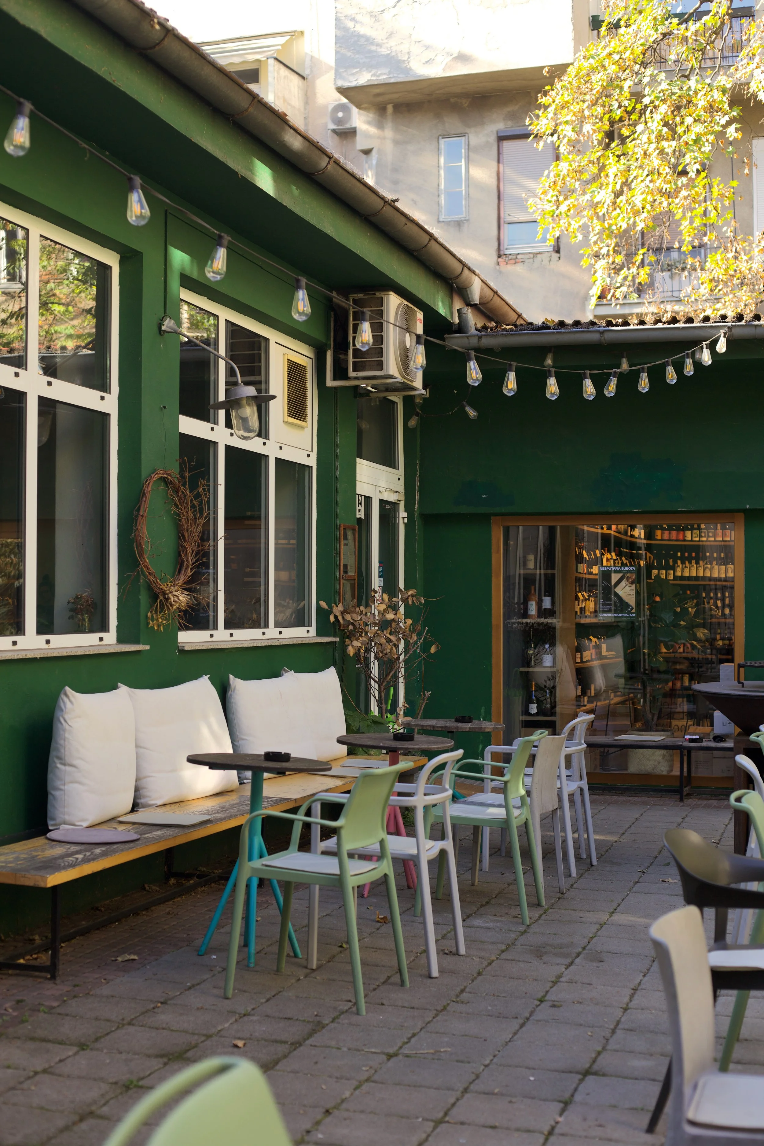 cafe in a courtyard, string lights, green, natural wine