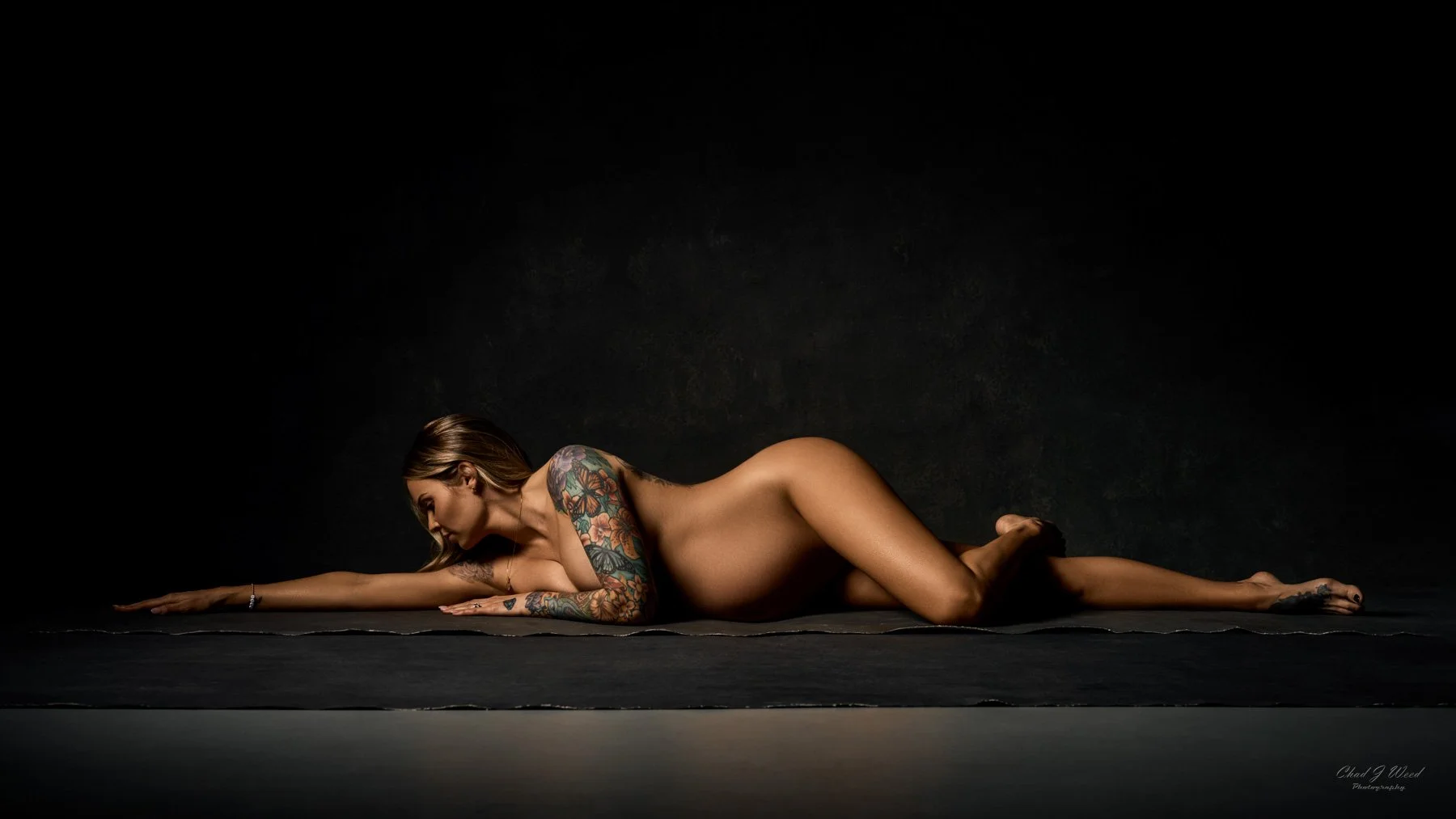 Nude Maternity Boudoir Photography Phoenix: Pregnant woman in a minimalistic nude pose, with soft shadows highlighting her shape