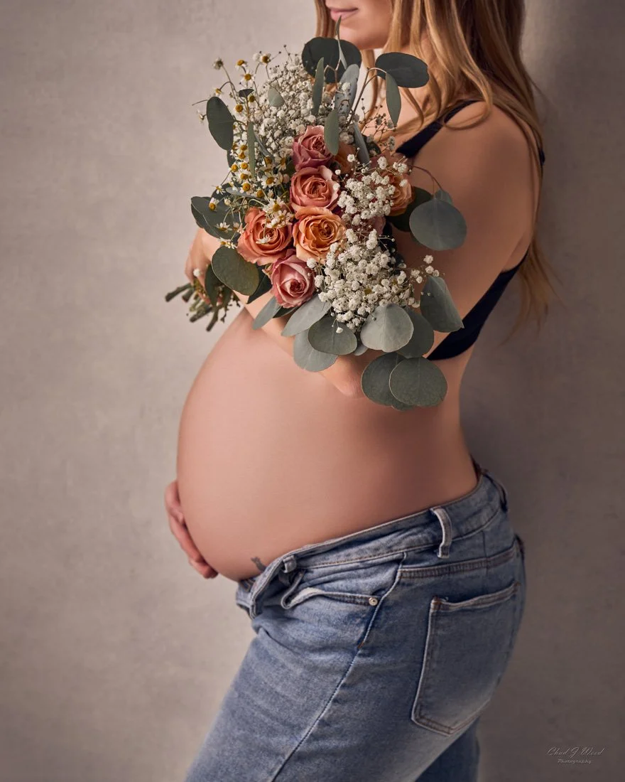 Pregnancy Photography Phoenix: Close-up of hand on pregnant belly and bouquet of flowers