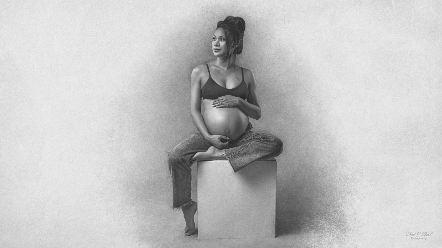 Fine Art Maternity Photography Phoenix: Pregnant woman in a studio, holding her belly with a peaceful smile
