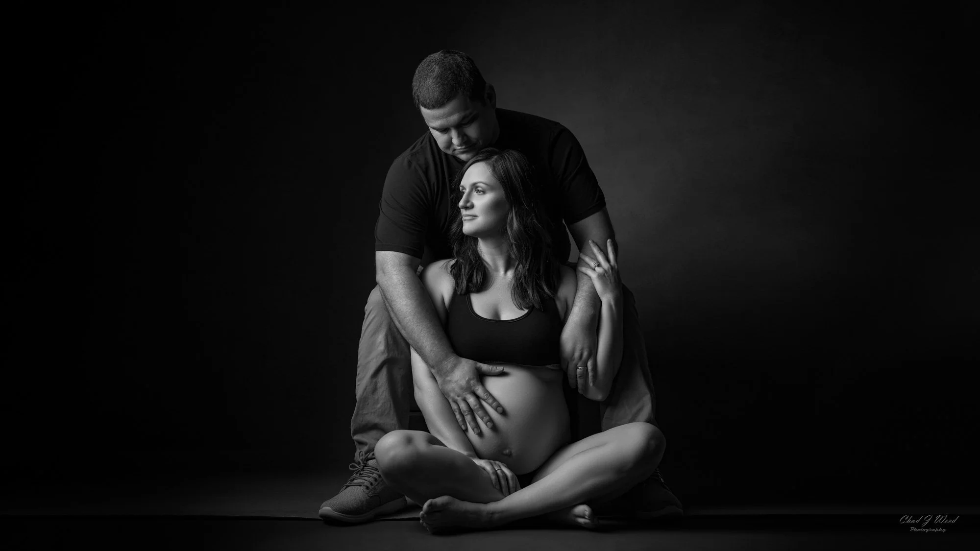 Phoenix Maternity Photographer: Mother-to-be sitting on the floor with her partner's arms around her