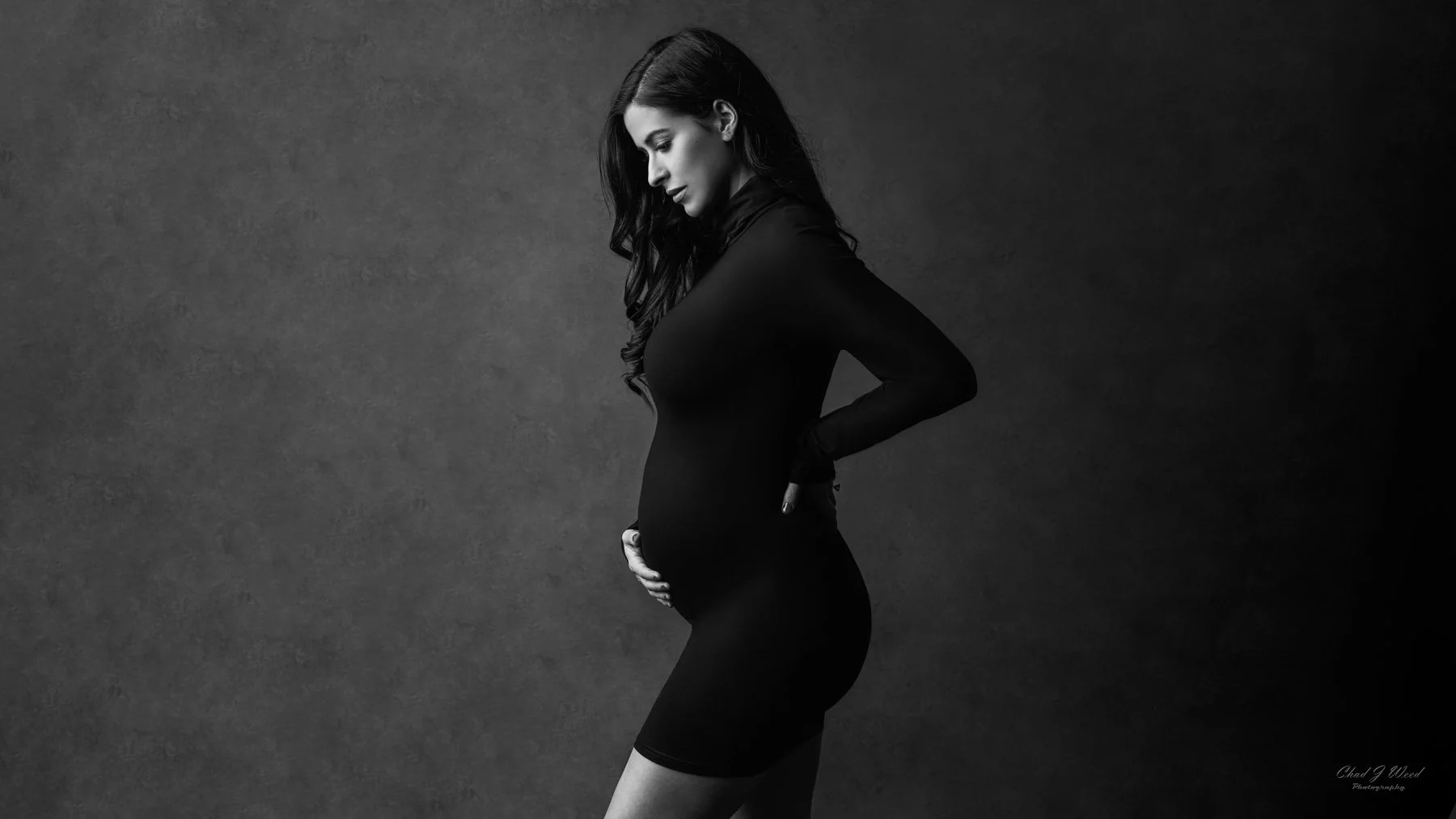 Mesa Maternity Photoshoot: Pregnant mom in a tight black dress, posing with elegance in a studio