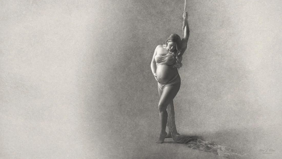 Fine Art Pregnancy Photography Scottsdale: Pregnant woman draped in a flowing fabric, with dramatic lighting in the studio