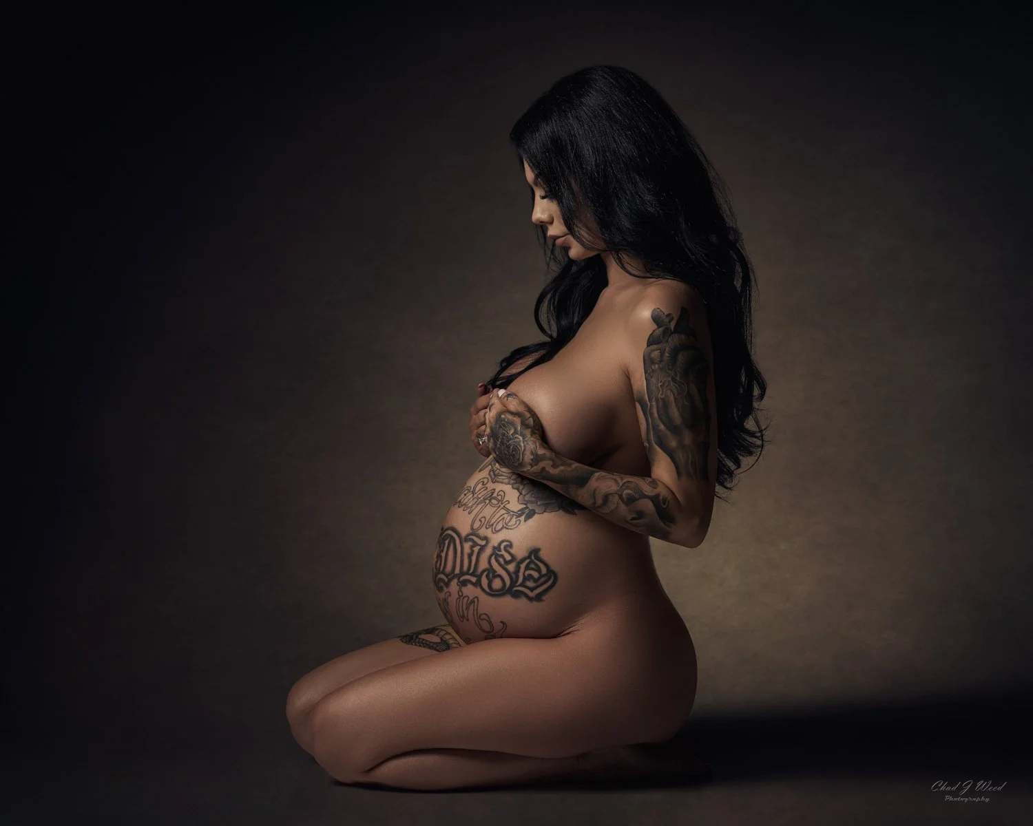 Maternity Photography of Pregnant kneeling woman's figure with artistic side lighting