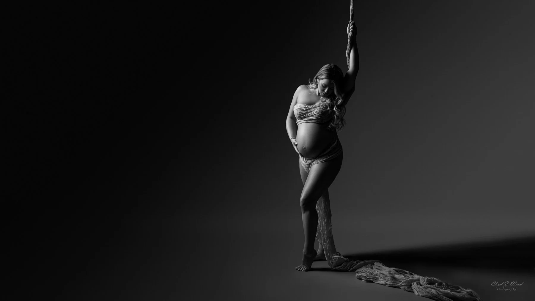 artistic fine art mesa maternity photography session with pregnant woman wrapped in fabric hanging from the ceiling