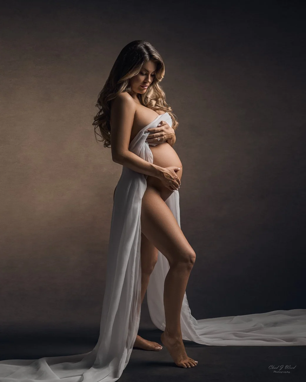 Standing with fabric wrap holding the belly maternity pose