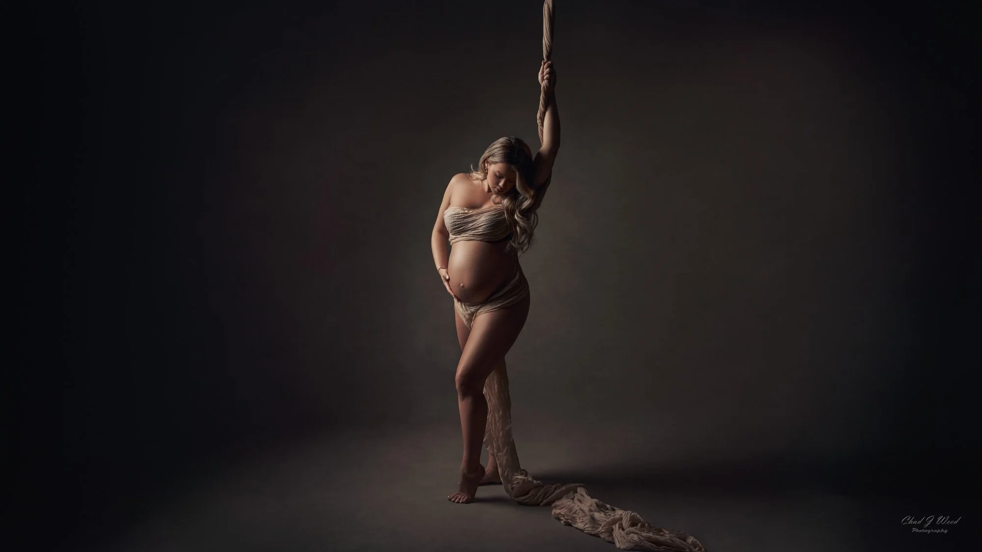 Intimate Maternity Photography: Pregnant woman holding her belly in a serene studio setting