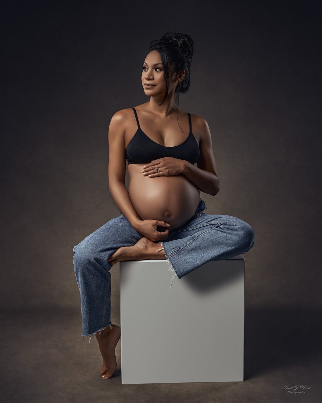 Mesa maternity photographer casual fashion style in jeans sitting on a white box