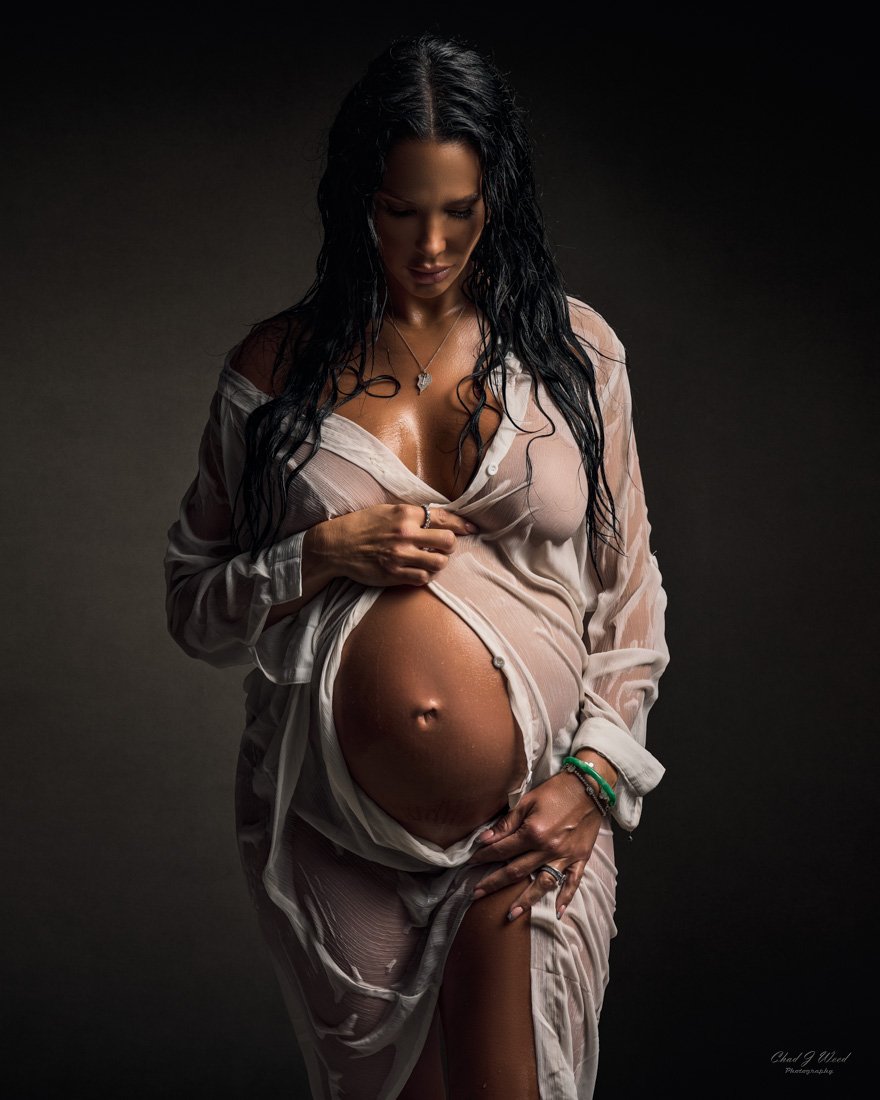 Fine Art Maternity Photography: Pregnant woman in a studio, with a dramatic light highlighting her belly