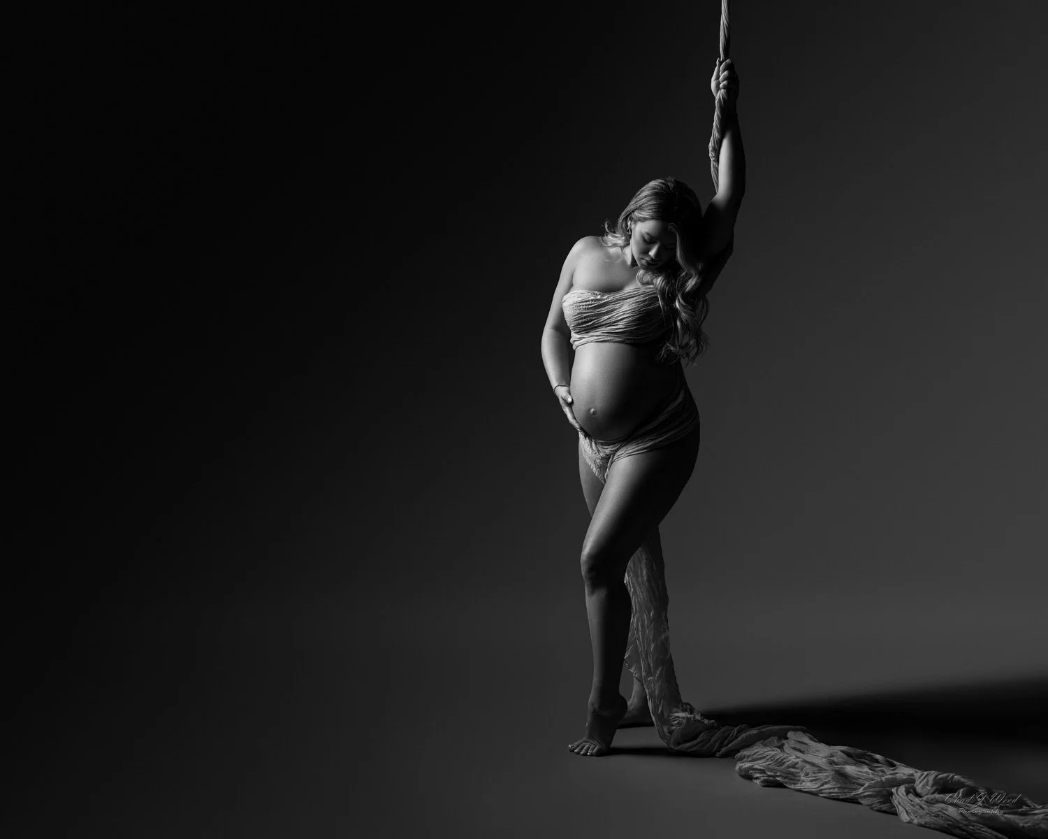 Local Pregnancy Photographer Mesa: Expectant mother with a hand on her belly, surrounded by delicate, artistic lighting