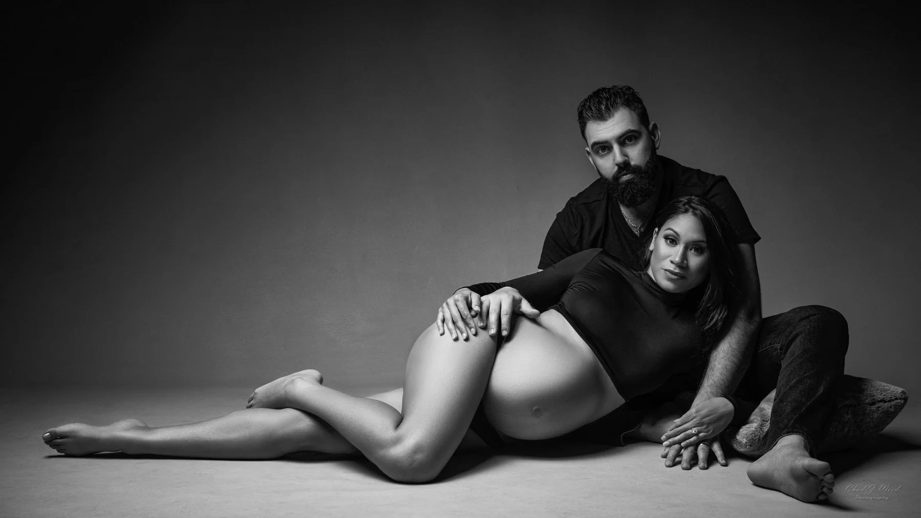 Couples maternity photography session in dramatic studio lighting