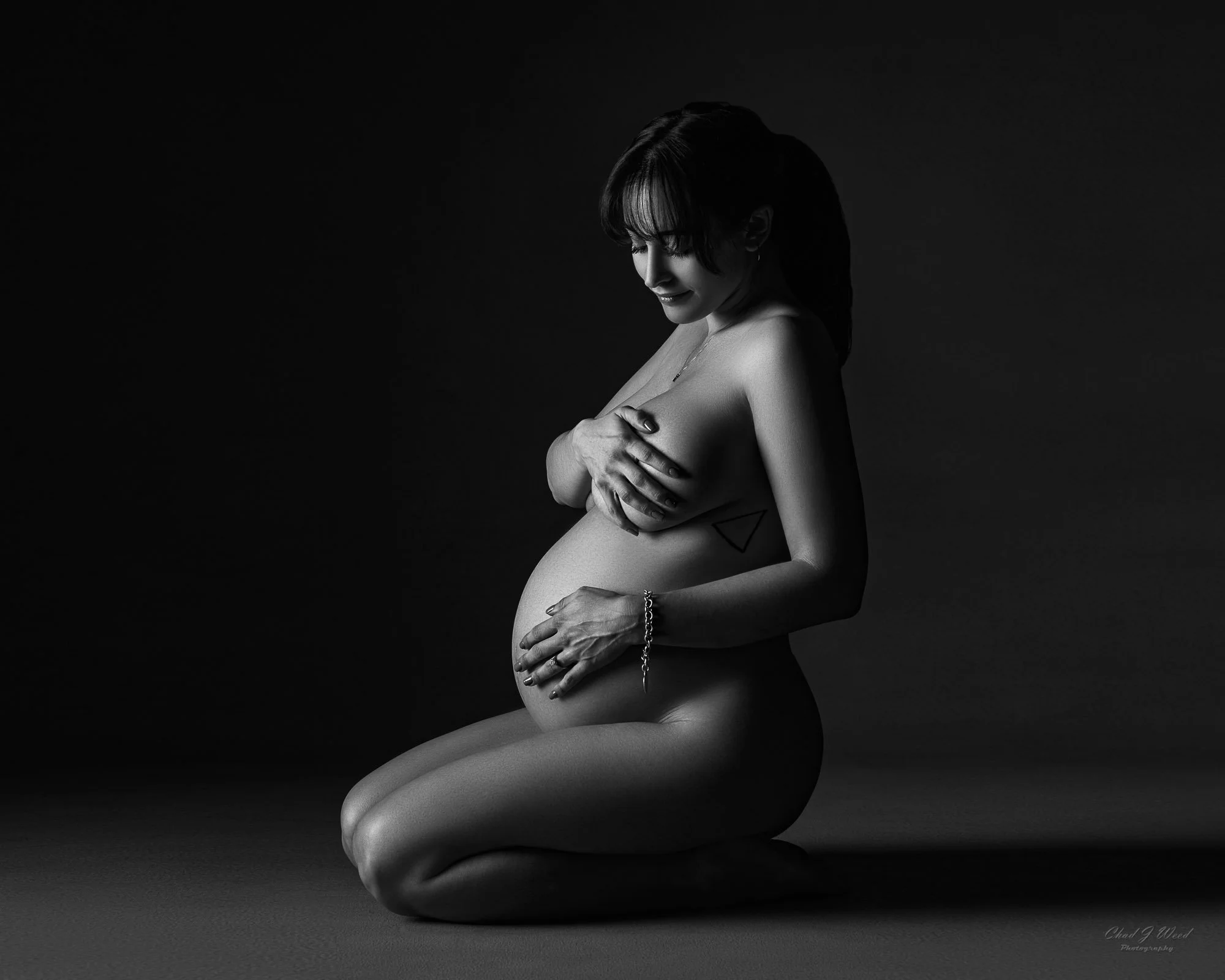 Kneeling side profile maternity photography pose in black and white
