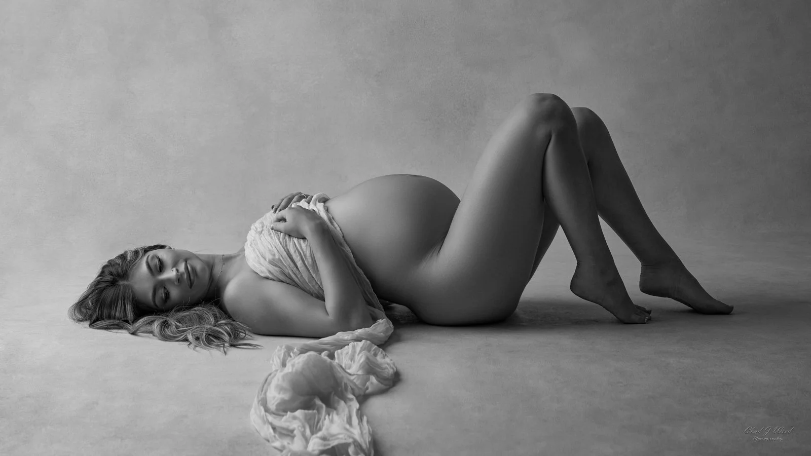 Phoenix Maternity Photographer: Artistic maternity photo with dramatic studio lighting and a silk wrap