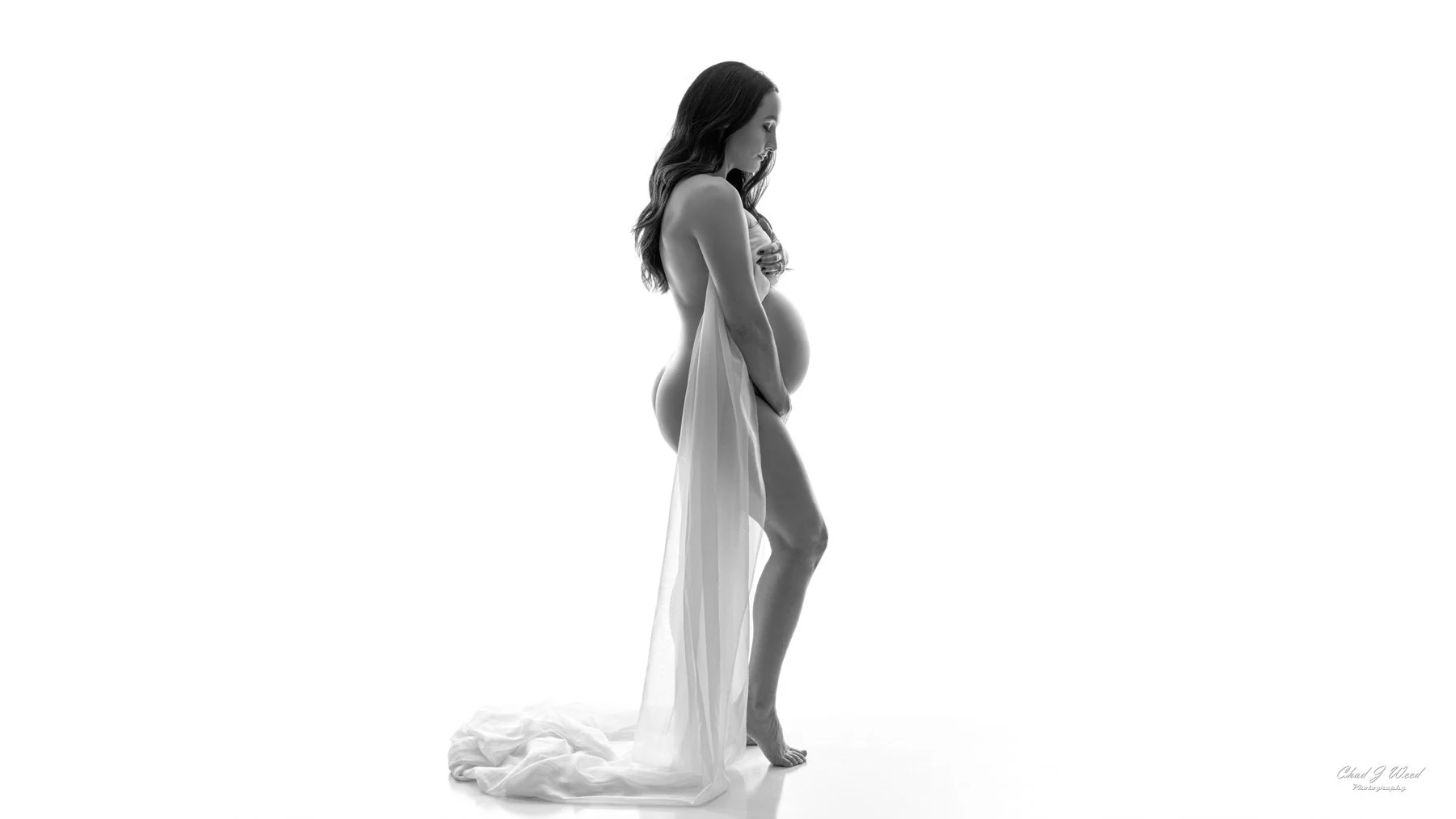 Standing maternity boudoir pose with silk material