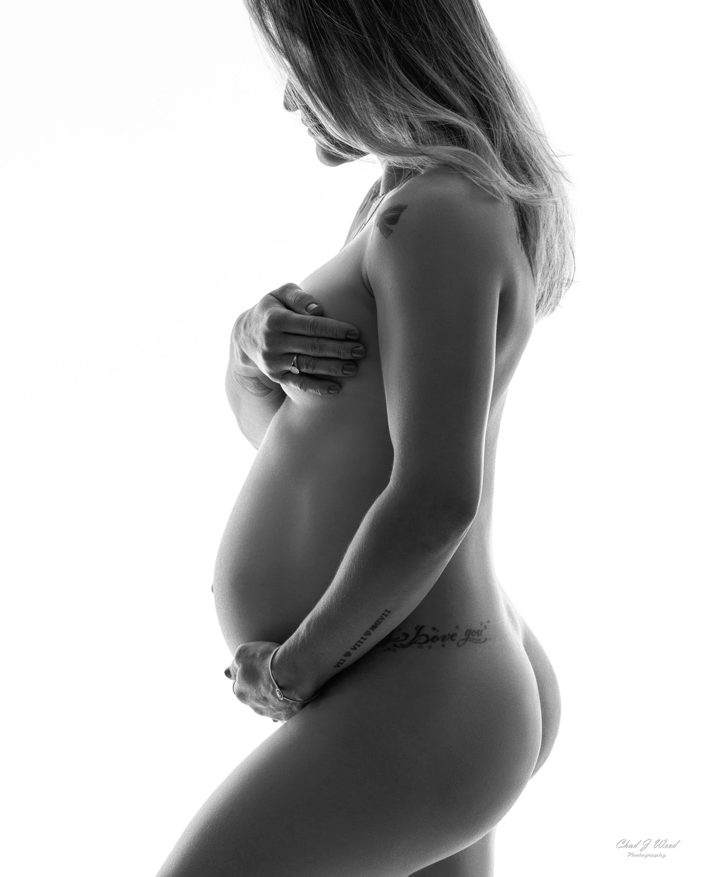 Close-up of expecting mom’s belly in maternity boudoir session pose