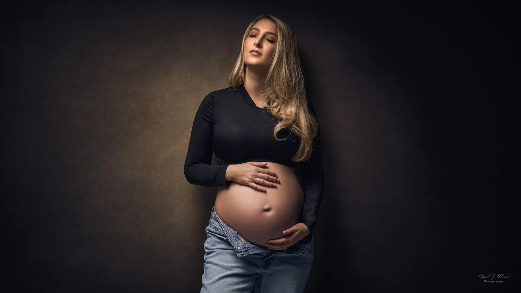 Maternity Photoshoot in Jeans: Pregnant woman wearing jeans holding baby bump