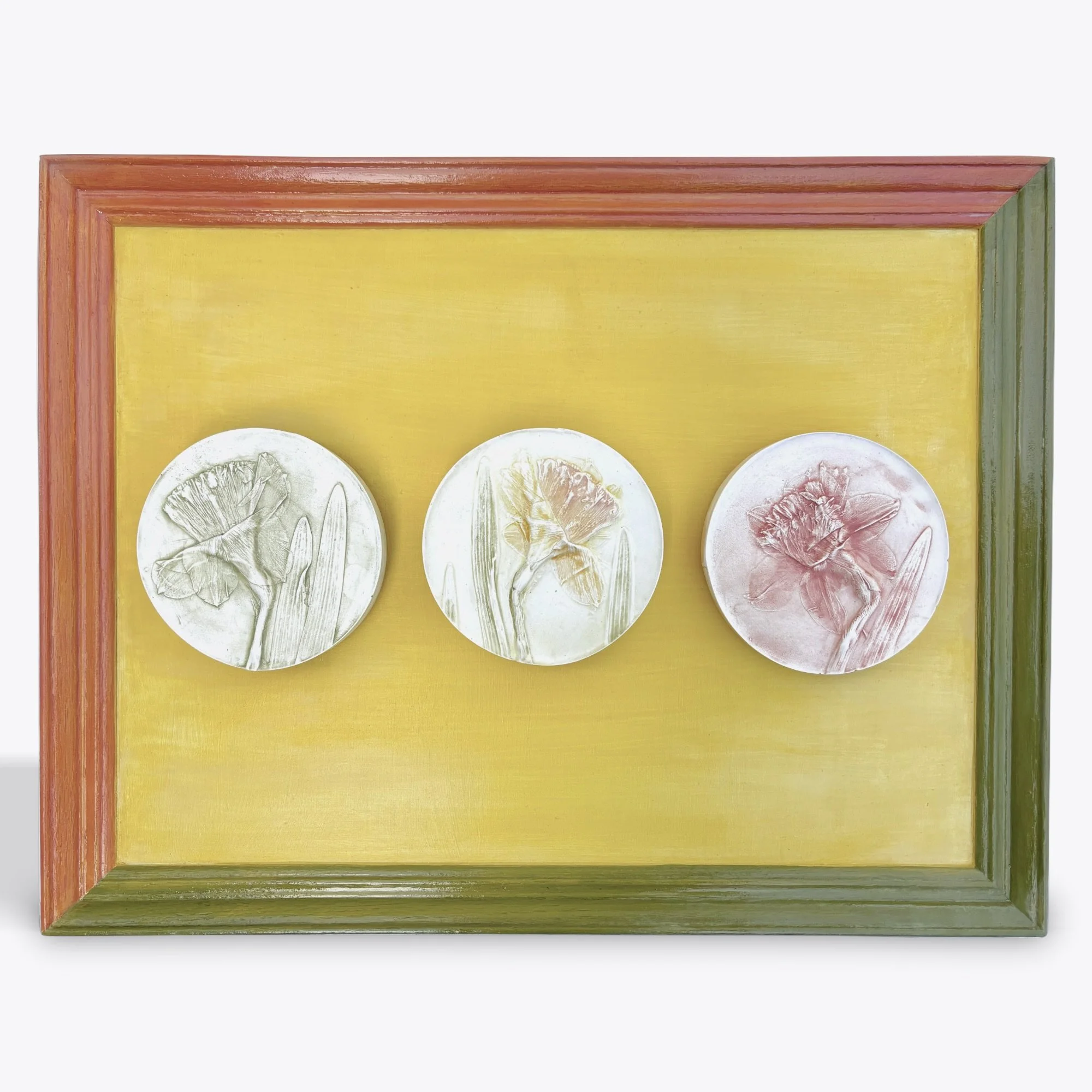  Three Daffodils, plaster, milk-paint on wood frame, 13.75in x 17.75in x 1in    Three daffodils stand out on a field of yellow bordered in a vintage frame uniquely painted in bold green and coral tones.    Available — $265 