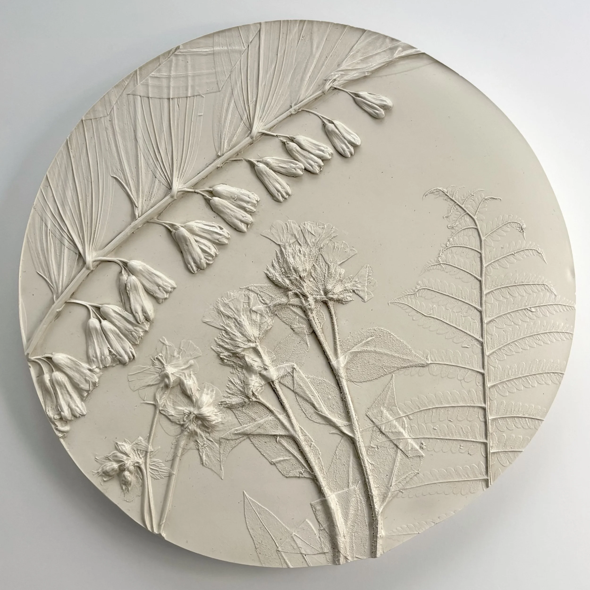  A Quiet Unfurl No. 1, milk-paint topcoat on hydrostone, 9.75in round x 0.6in (ready to hang with picture-wire on back)   This artwork captures a serene moment in nature, blending spring botanicals and delicate plants to evoke a sense of calm and int