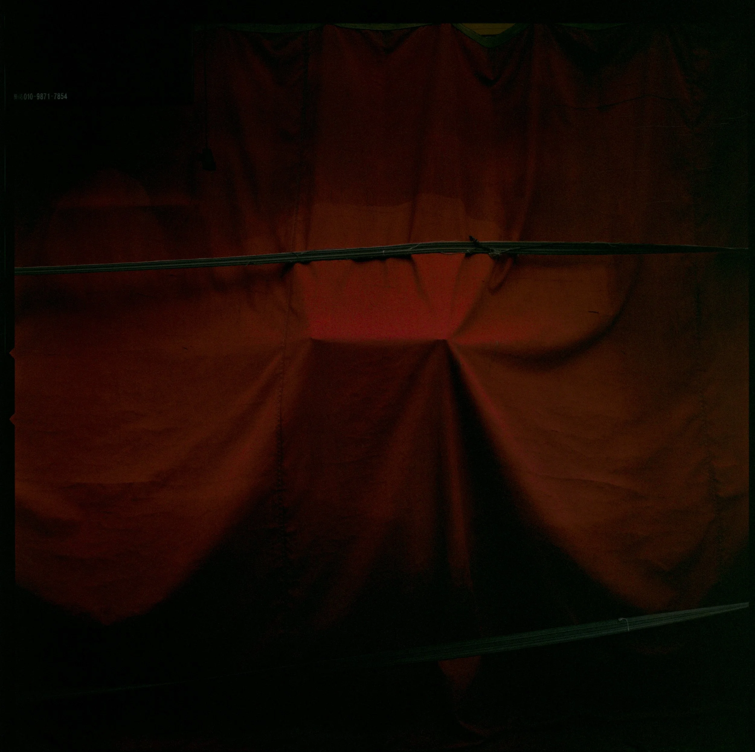 Tela de color rojo con líneas negras y una cuerda horizontal en medio.