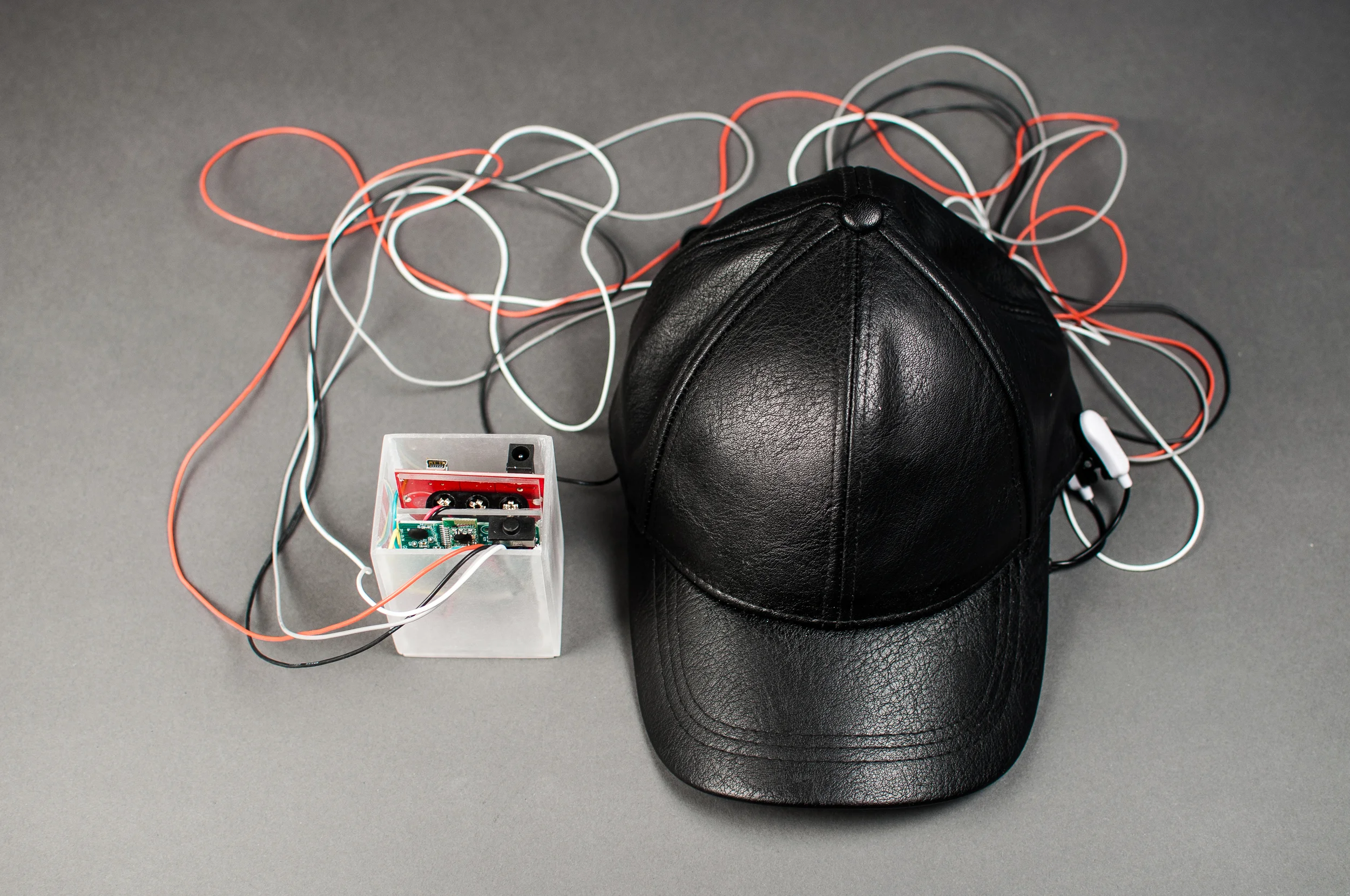 PROSTHETE's hardware: an EEG sensor is embedded in the cap; a hacked Neurosky chip sends serial data to an Arduino clone board which then parses the signal and sends it to an attached laptop.
