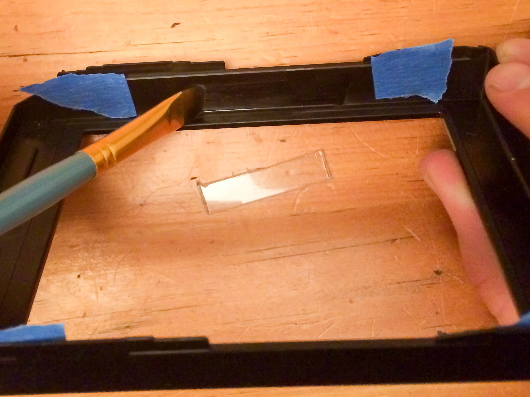 After brushing on the adhesive, press and hold the widest side the of your Lexan to the center of your markings on the wall of the Polaroid pack. Make sure you adhere 1/16 inch width Lexan stated above or you will have trouble with your plate fitting. 