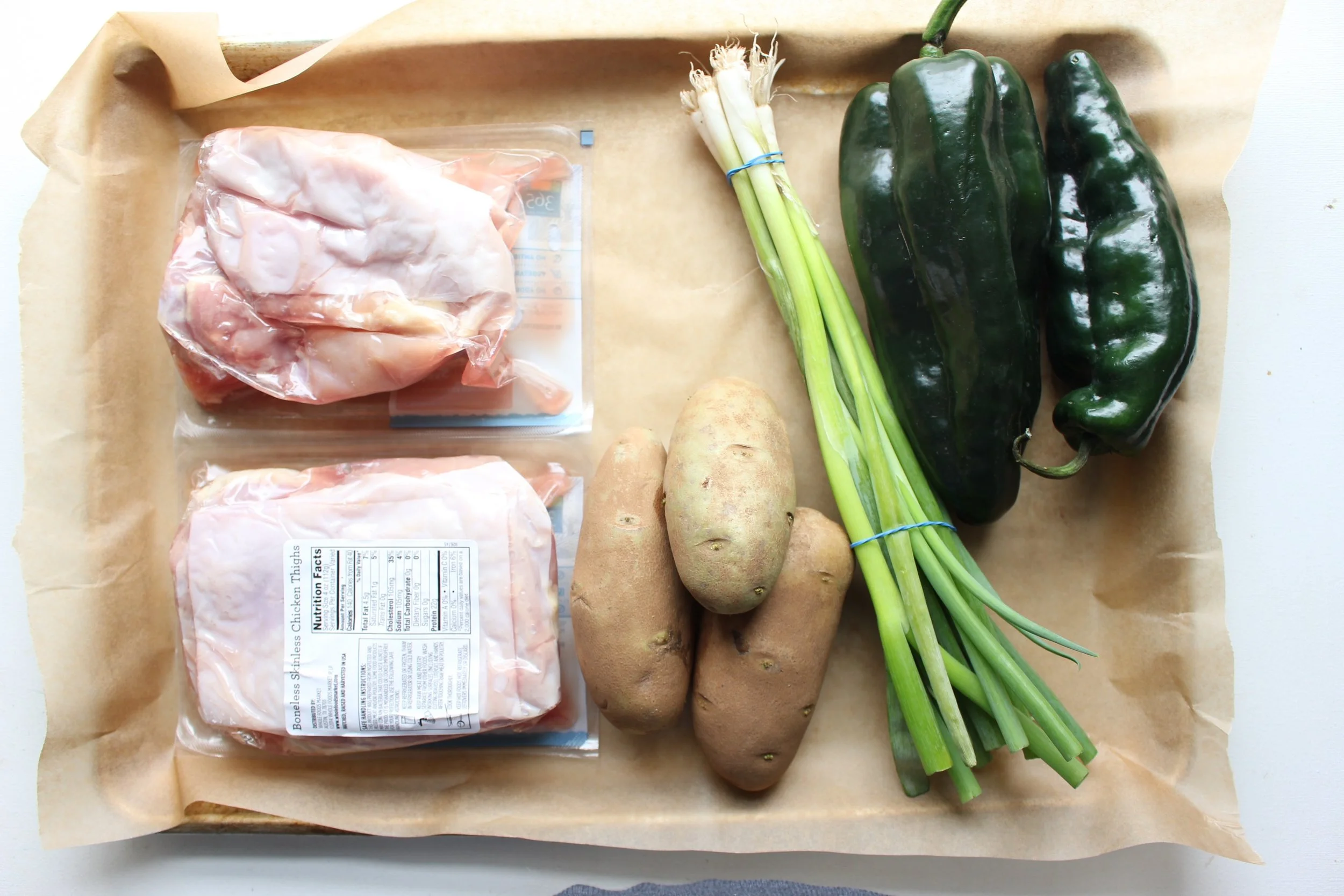 Ingredients list: chicken thighs, scallions, poblano peppers, and potatoes. Add olive oil and a Tex-Mex spice mix for a sheet pan dinner that will please the entire family.