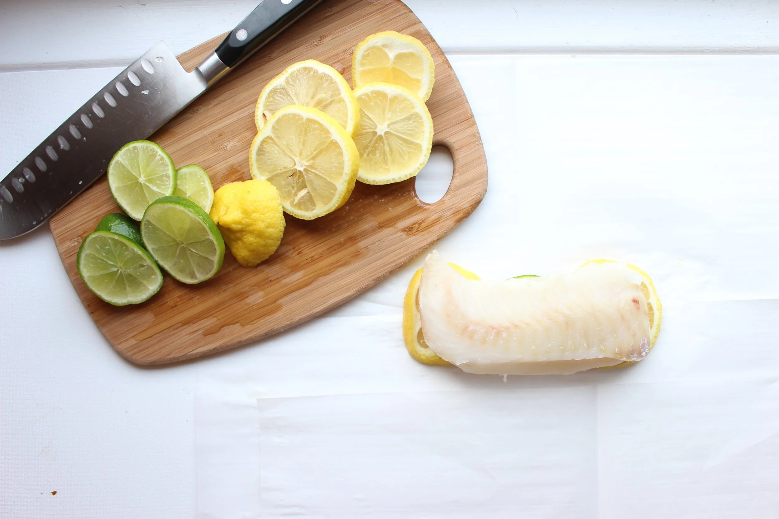 The white fish roasts on a bed of lemons and limes.