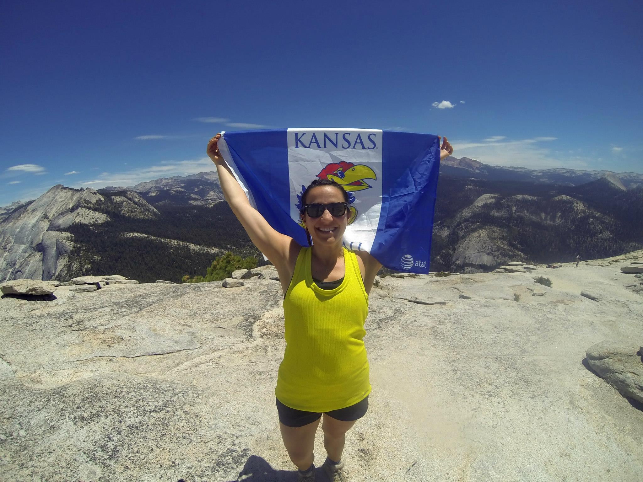 Blair showing Kansas Pride at the top of Half Dome, Yosemite. Photo Credit: Erik Anderson 