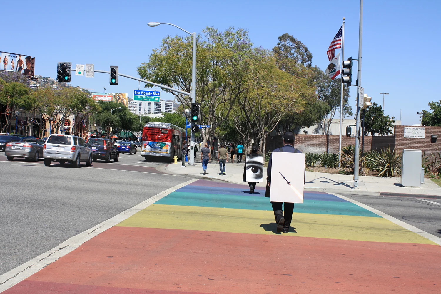 100 Walkers, West Hollywood , a large scale performance piece by Richard Kraft took place on April 18th 2015. One hundred people, each dressed in a dark suit and bowler hat and wearing a sandwich board (with a unique image on both front and back) walked pre-determined routes through the city. The piece began with all one hundred walkers forming a grid in the El Tovar parking lot adjacent to West Hollywood Park. Once all one hundred walkers were in place, the maestra of ceremonies Marjorie Perloff began calling "start phrases" to release one walker at a time at approximately five second intervals. Once the walkers dispersed, they could be seen all over West Hollywood, particularly along all the main thoroughfares: Sunset, Santa Monica, Melrose, Beverly, San Vicente, Doheny, La Cienega, Crescent Heights and Fairfax. During the piece performers remained silent. Interaction with inquisitive passers by was confined to the handing out of a business card. The walk ended when all walkers returned to their starting point at the El Tovar parking lot, standing for one minute to finish their performance. For more images and further information please visit: www.onehundredwalkers.com Photo by Matt Stromberg