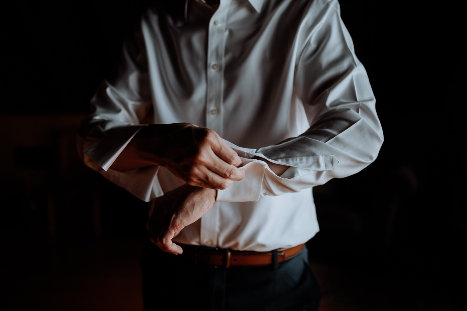 groom buttons shirt while getting ready at red maple vineyard we