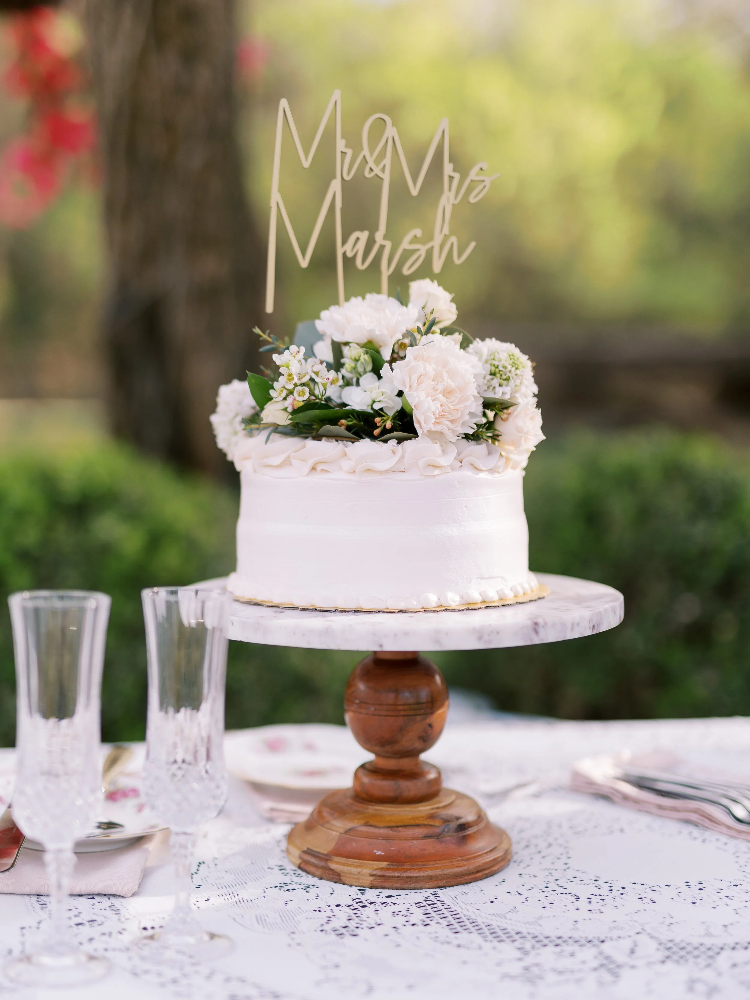 Wedding flowers at St. Catherine’s at Bell Gable, Fayetteville, AR by Rose of Sharon Floral Design Studio. Cake topper filled with fluffy white carnations and scabiosa. Photo by Emma Farr.