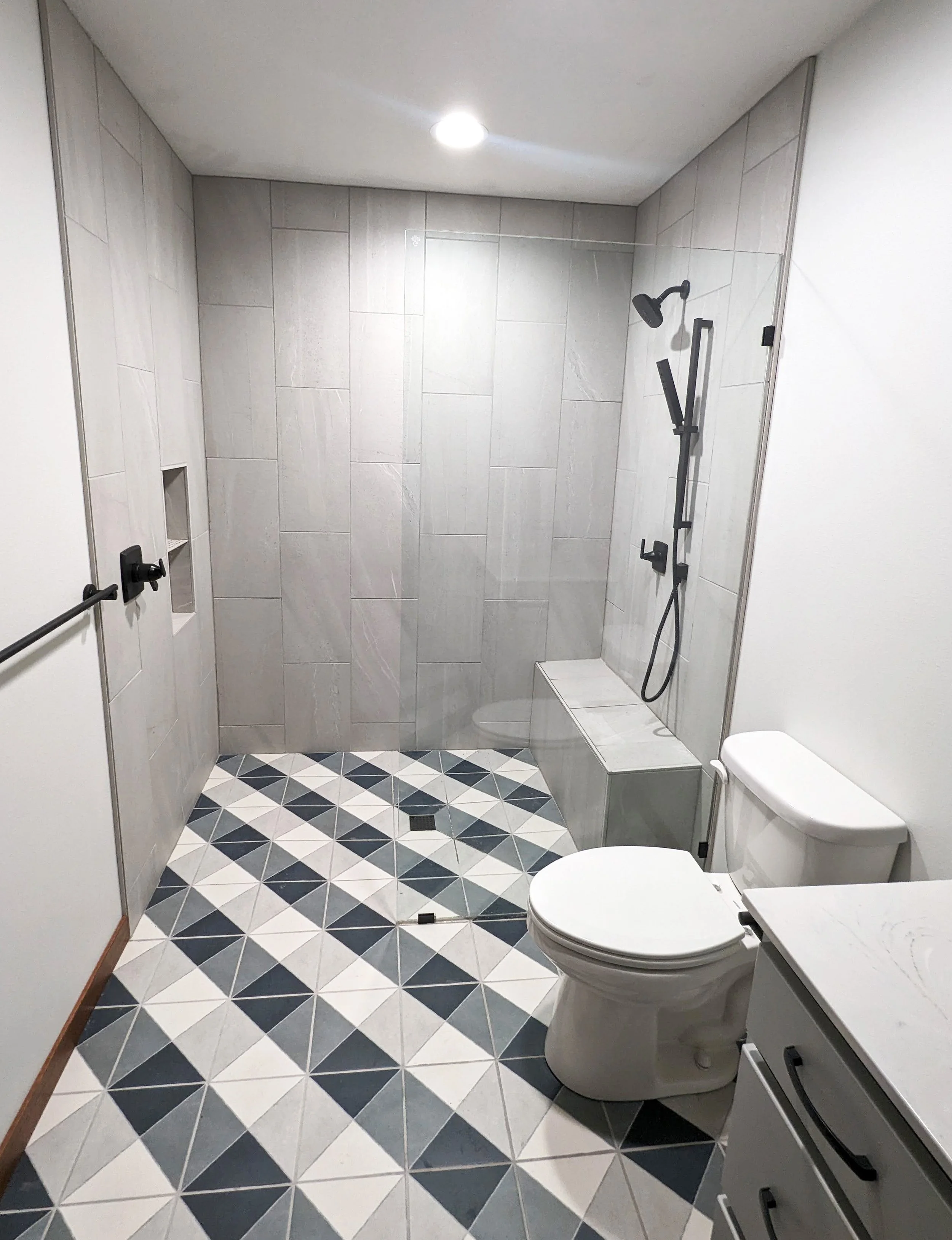 Modern bathroom with walk-in shower, white toilet, and patterned tile floor.