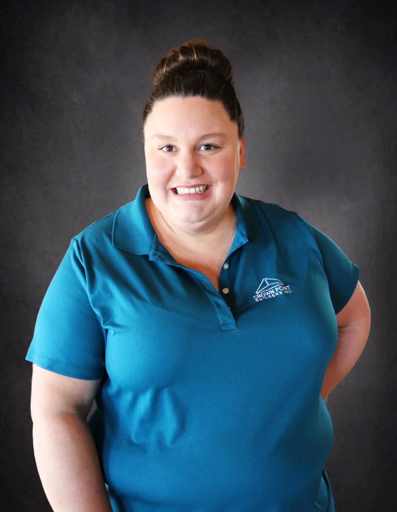 Woman smiling in teal polo shirt with company logo