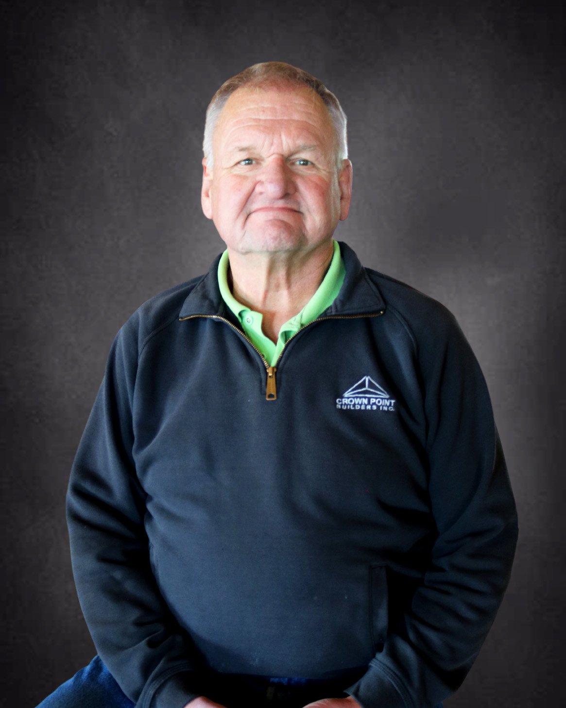 Portrait of a man wearing a dark jacket with "Crown Point Builders Inc." logo.