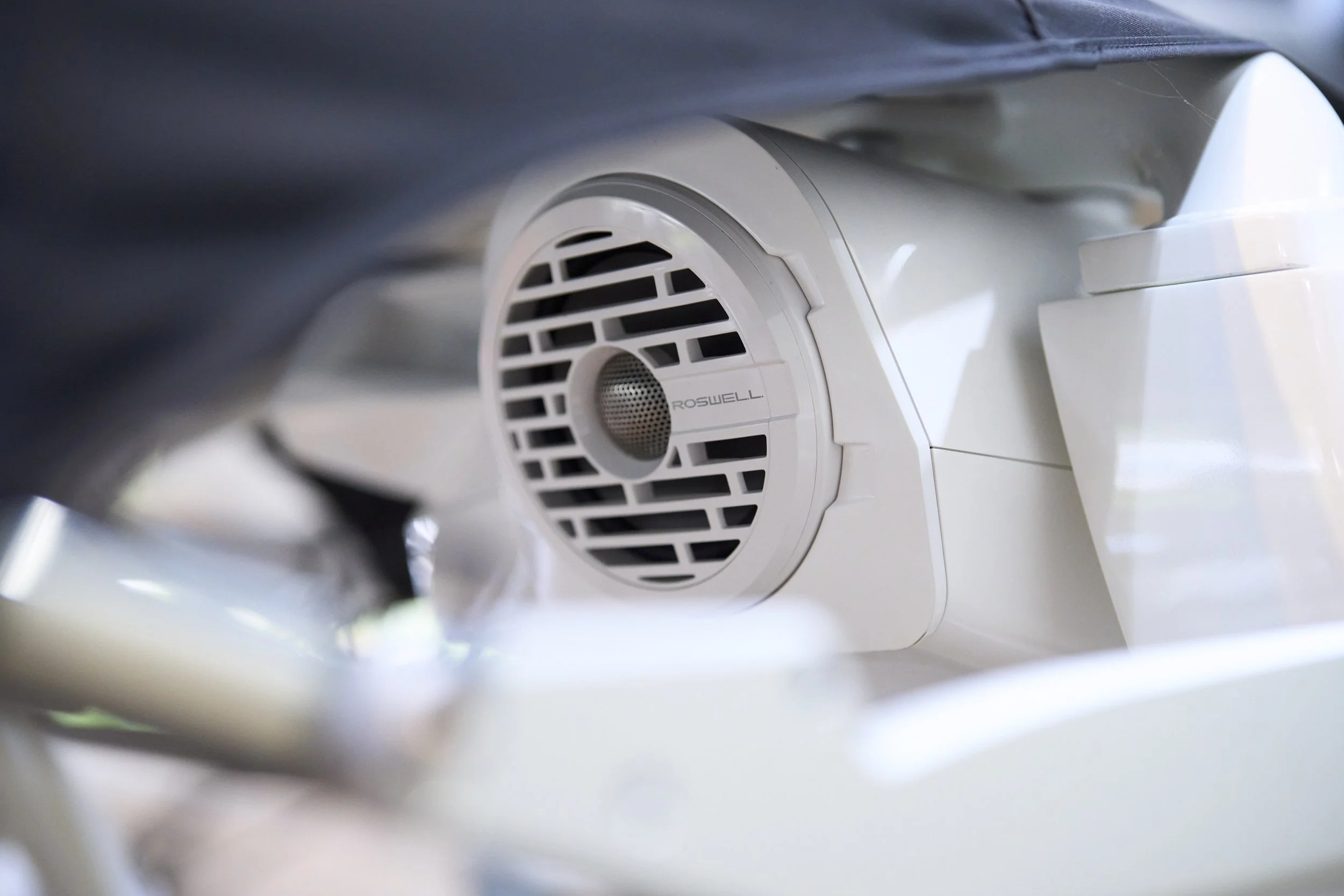 Close-up of a white RoSwell dental or medical device with a circular vent or filter, partially obscured by the surrounding equipment and dark cloth.