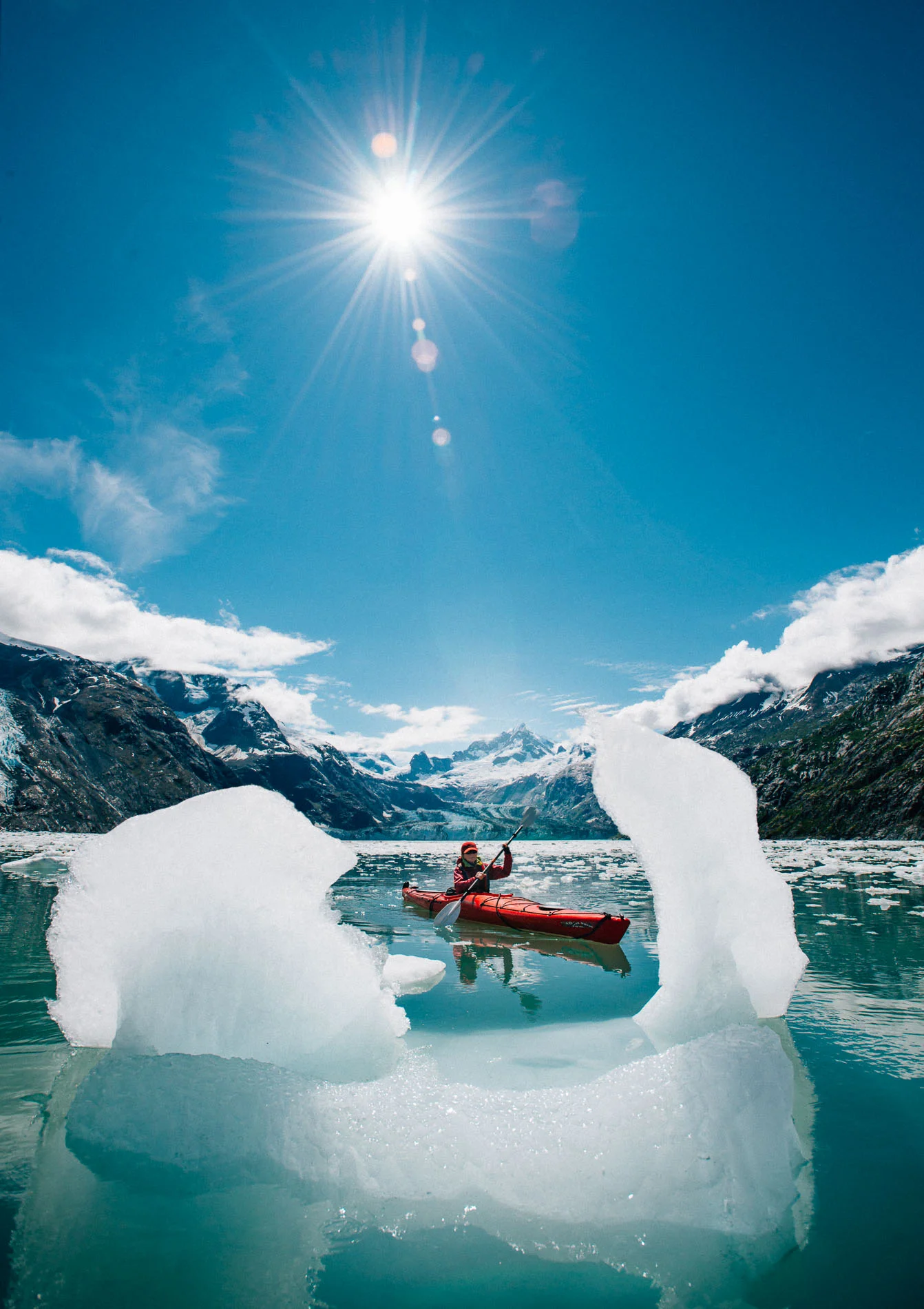 Woman kayaks in between icebergs, Glacier Bay, Alaska.