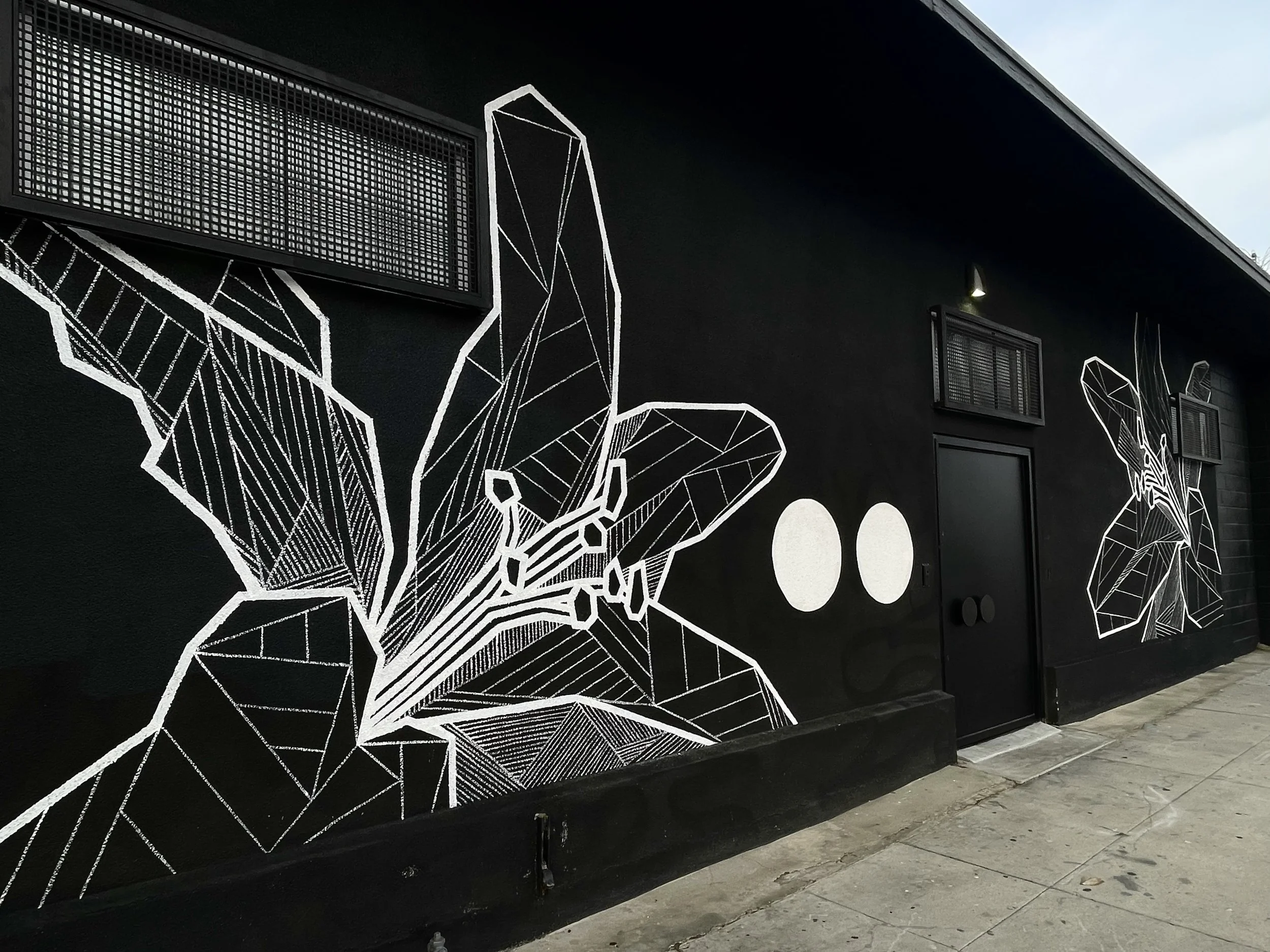 Black and white exterior mural of geometric lilies hand-painted by Allison Kunath.