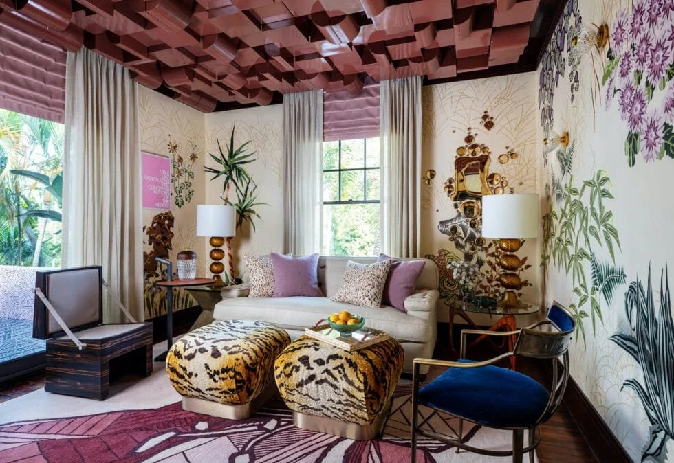 Eclectic living room with colorful patterned walls, white sofa, animal print ottomans, purple ceiling, and a mix of modern and vintage furniture.