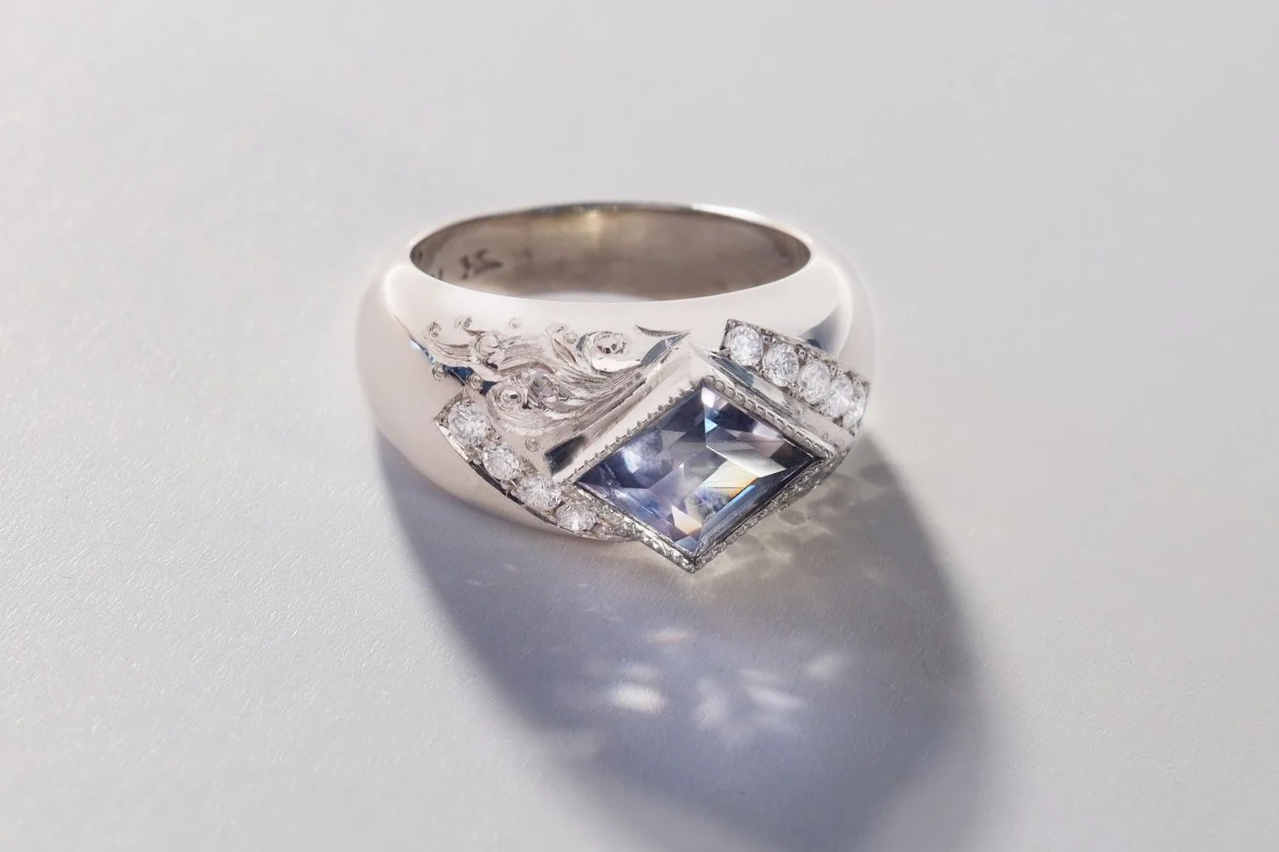 Lozenge cut sapphire, white diamonds and hand engraved waves in white gold