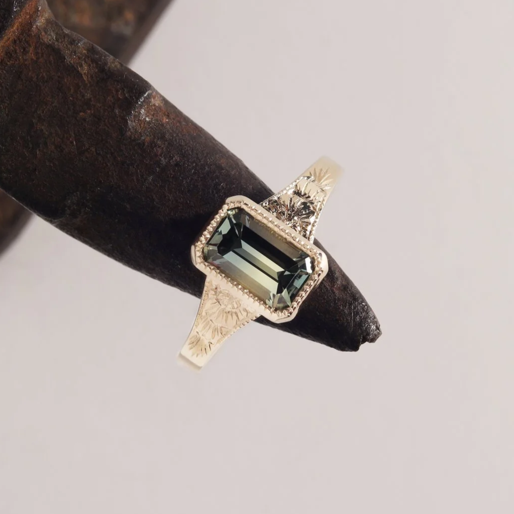 Emerald cut sapphire in hand engraved yellow gold