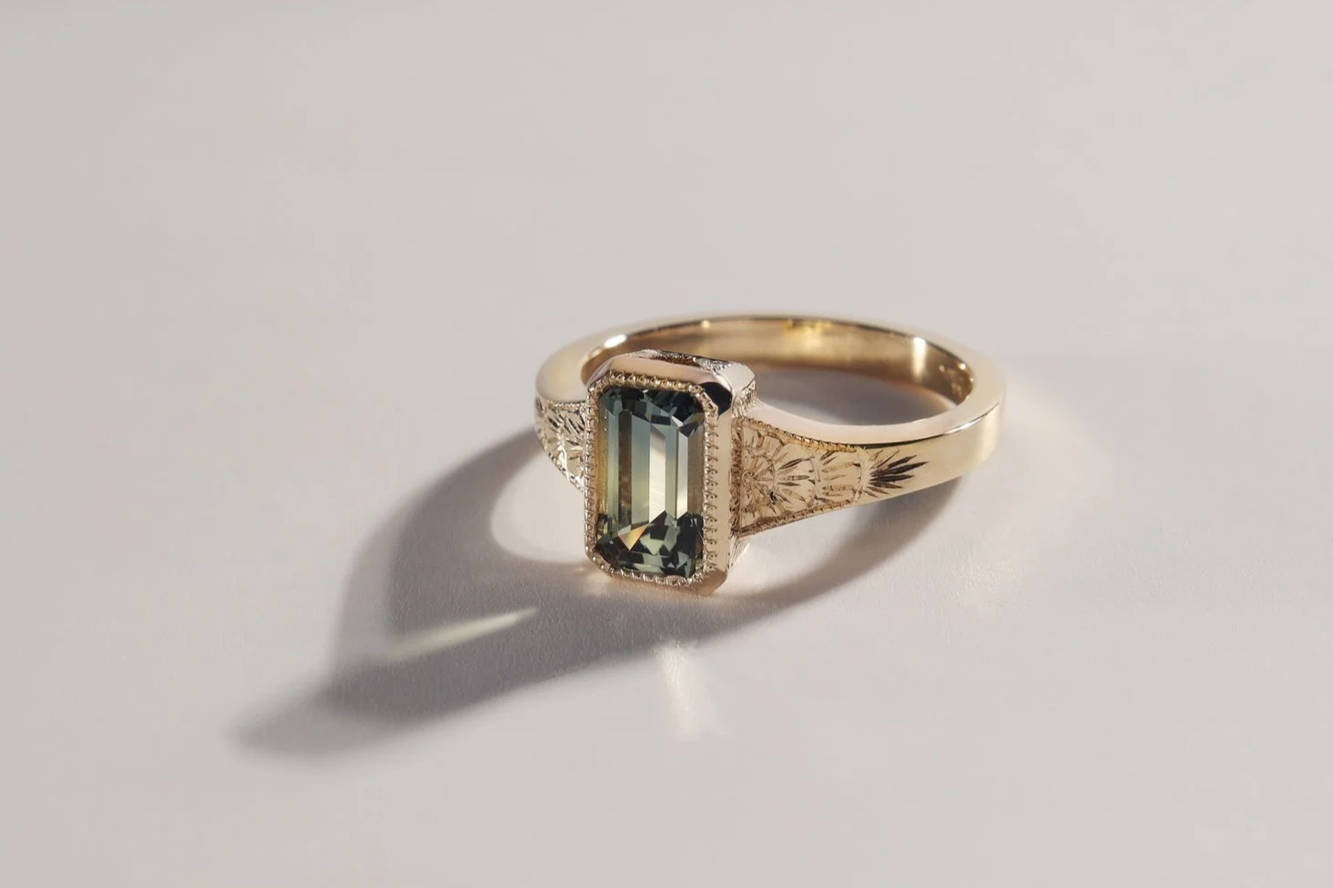 Emerald cut sapphire in hand engraved yellow gold
