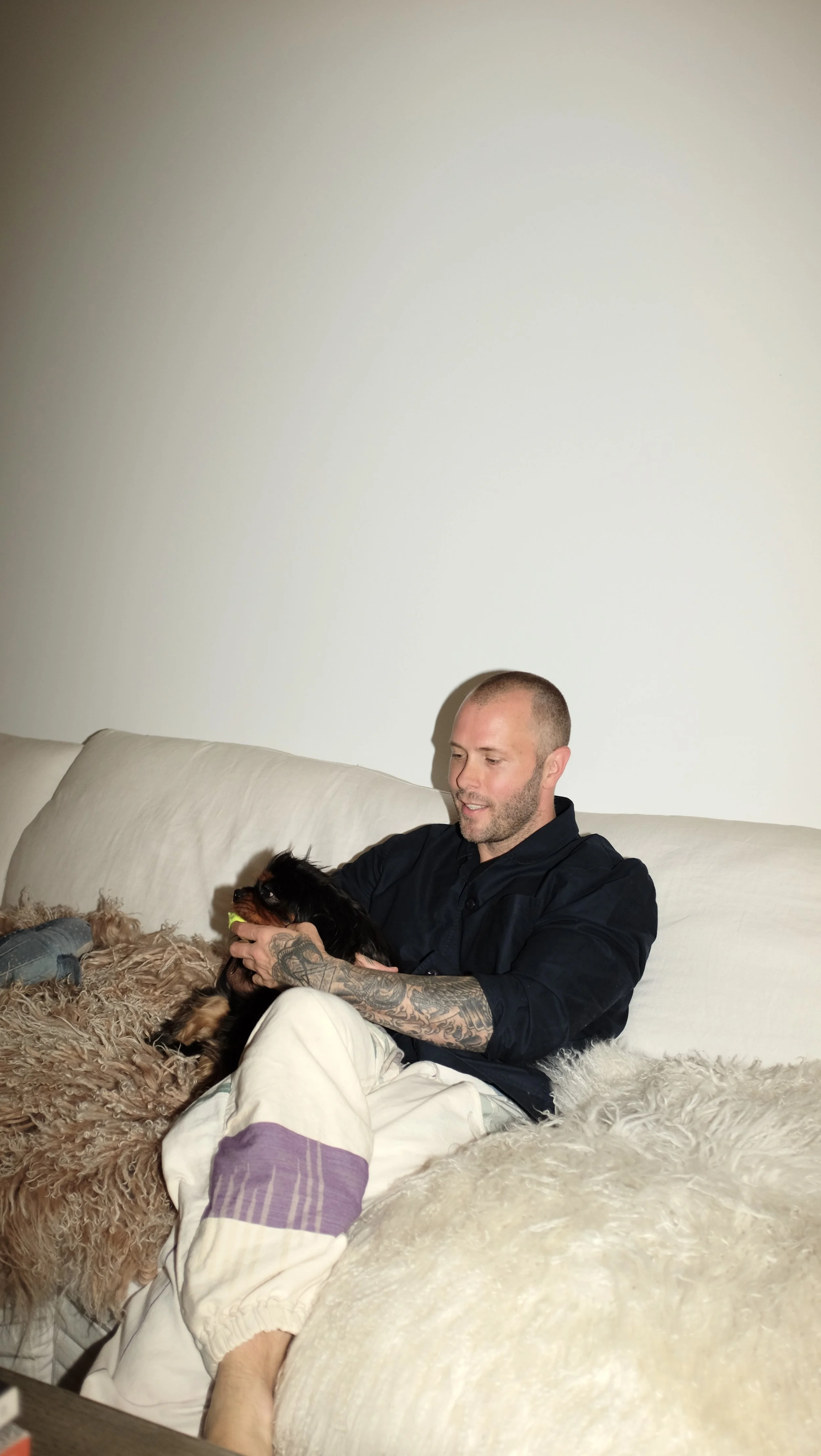 Mike Bagale with dog on couch wearing black chef coat designed by Finery.