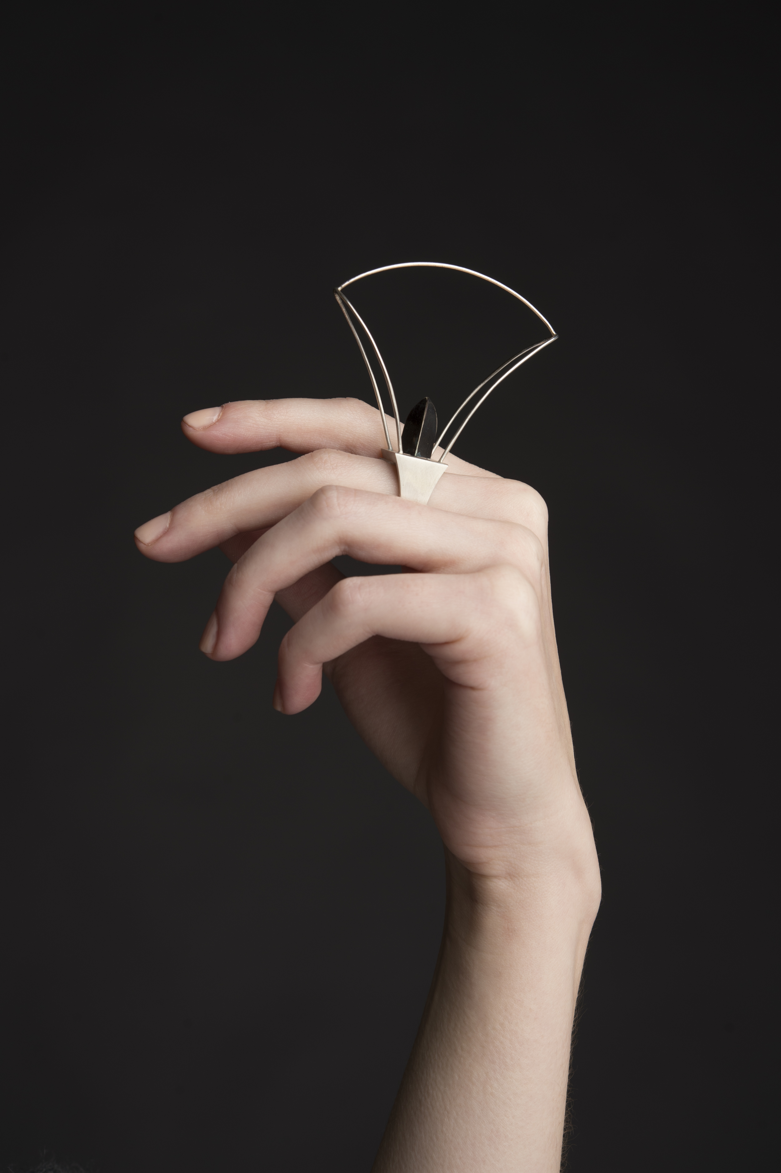Created primarily as an exploration of form, this pair of sculptural rings are hollow-constructed out of sterling silver and shibuichi, an alloy which I made for this piece. The “stone” in the wire-frame ring is another hollow form, also made of shibuichi, which is hand-threaded and screws into place. The forms of these rings were influenced by tool forms and mathematical functions. 2.25"x.75"x2.75" 2013